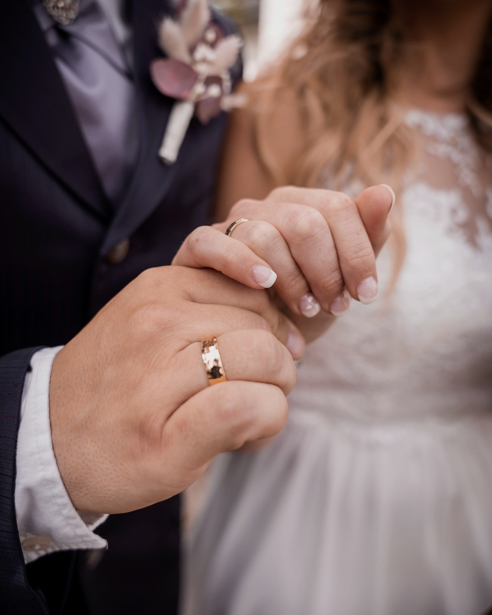 Trauringe an den Händen eines Hochzeitspaars